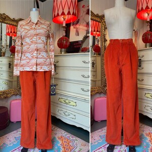 May include: A vintage ensemble featuring a long-sleeved button-up shirt with a peach and white pattern, paired with high-waisted, wide-leg orange corduroy pants. The outfit is displayed on a mannequin, showcasing a retro style.