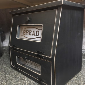 BREAD BOX The top compartment features a Frosted and Laser Engraved Plexiglass front saying "BREAD" and will fit 2 full size loaves. The other bin has a Plexiglass SNACKS and perfect for storing chips, cookies and so much more!