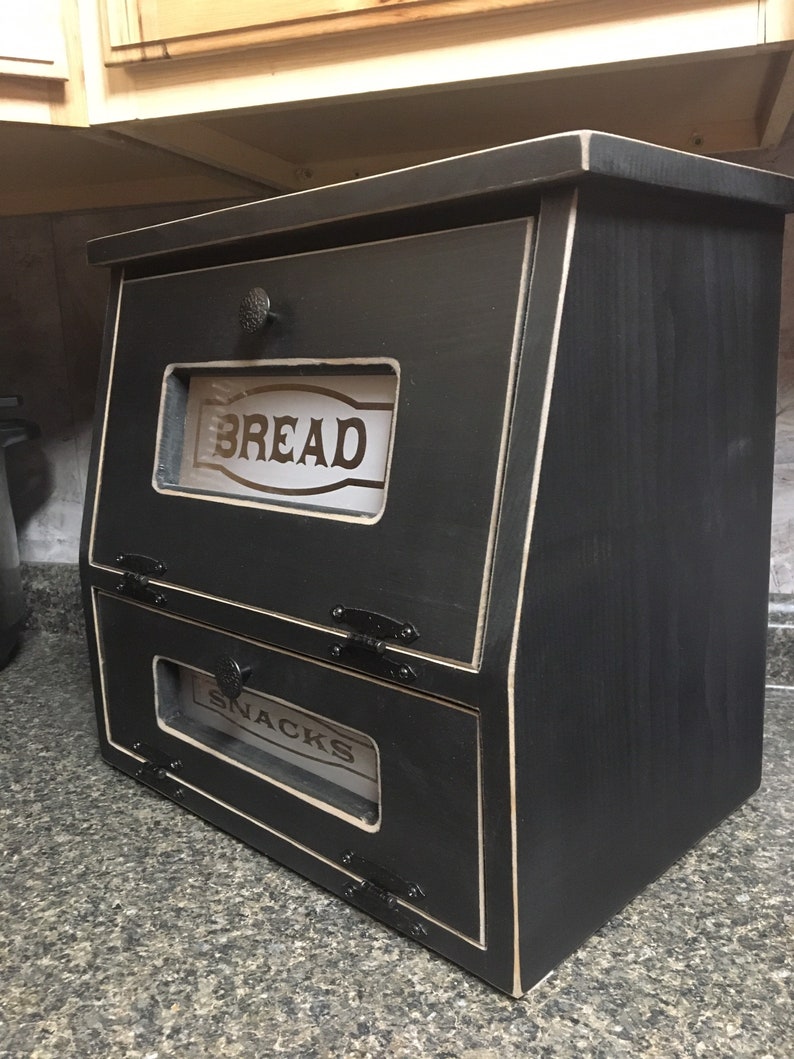 BREAD BOX The top compartment features a Frosted and Laser Engraved Plexiglass front saying "BREAD" and will fit 2 full size loaves. The other bin has a Plexiglass SNACKS and perfect for storing chips, cookies and so much more!