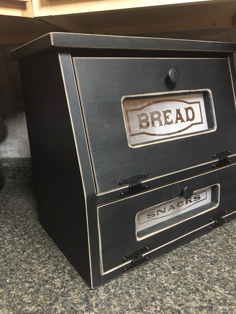 BREAD BOX The top compartment features a Frosted and Laser Engraved Plexiglass front saying "BREAD" and will fit 2 full size loaves. The other bin has a Plexiglass SNACKS and perfect for storing chips, cookies and so much more!