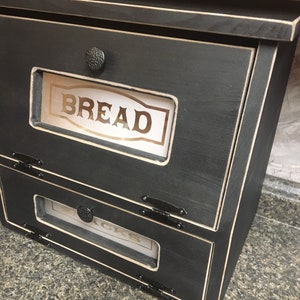 BREAD BOX The top compartment features a Frosted and Laser Engraved Plexiglass front saying "BREAD" and will fit 2 full size loaves. The other bin has a Plexiglass SNACKS and perfect for storing chips, cookies and so much more!