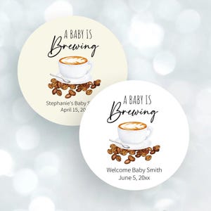 May include: Two round stickers with the text "A Baby Is Brewing". Each sticker features a coffee cup with coffee beans. One sticker says "Stephanie's Baby S April 15, 20" and the other says "Welcome Baby Smith June 5, 20xx".