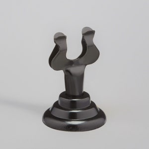 May include: Black metal table number holder with a U-shaped top and a round base.