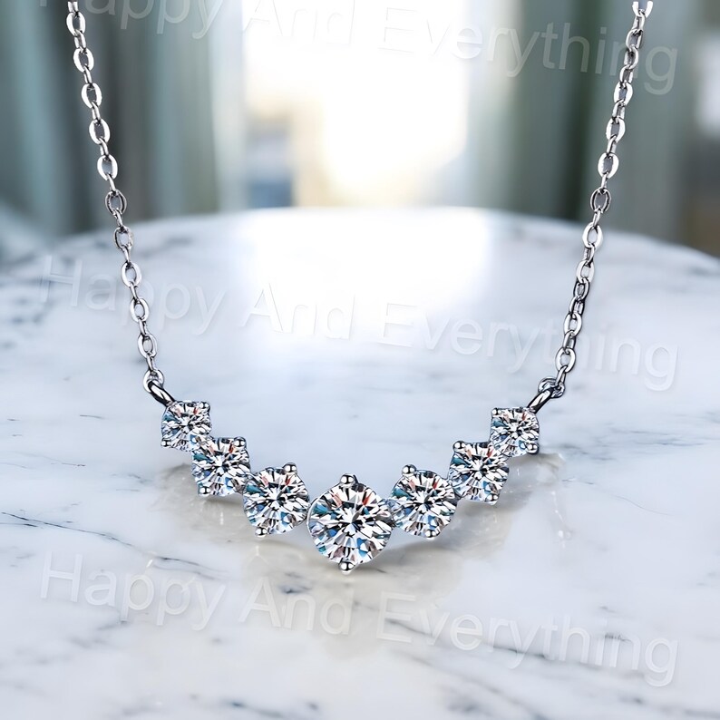 May include: A silver necklace with a curved row of five clear round cubic zirconia stones.