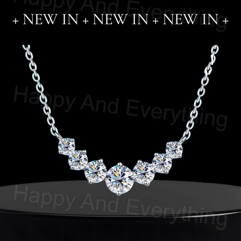 May include: A silver necklace with a curved row of five clear round cubic zirconia stones.