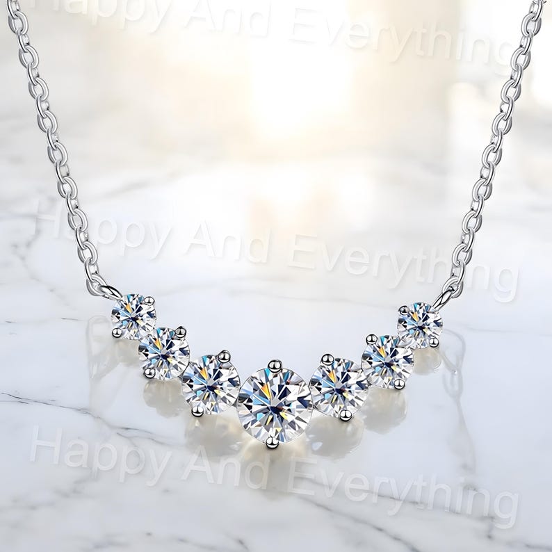 May include: A silver necklace with a curved row of six clear round cubic zirconia stones.