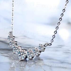 May include: A silver necklace with a curved row of five clear cubic zirconia stones.