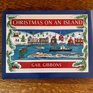 May include: A blue book cover with a white border and a colorful illustration of a snowy island village with houses on stilts and a boat in the water. The title "Christmas on an Island" is in red letters and the author "Gail Gibbons" is in red letters.