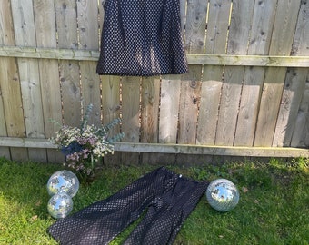 May include: A black sleeveless top and matching trousers with a gold glitter pattern. The top has a round neckline. The trousers are wide-legged and have a high waist.