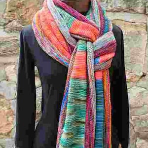 Puede incluir: Una bufanda de rayas coloridas con tonos de naranja, azul, verde y rosa. La bufanda está envuelta alrededor del cuello de un maniquí y está atada en un nudo flojo.