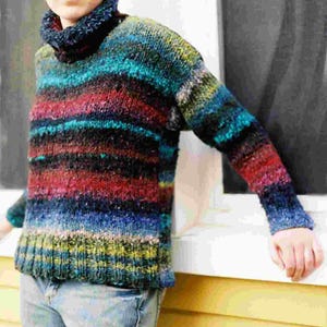 May include: A person wearing a colorful striped sweater with a turtleneck collar and blue jeans.