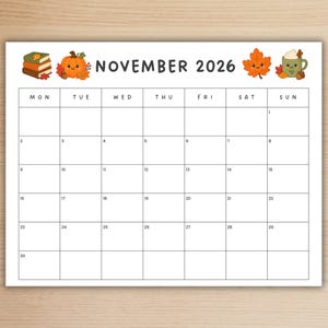 May include: A November 2026 calendar page featuring a white background with a black grid. The header displays the text NOVEMBER 2026, flanked by illustrations of a stack of books, a smiling orange pumpkin, a smiling maple leaf, and a green mug.