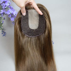 Pode incluir: Um topper de cabelo humano castanho com base de renda. O topper é projetado para adicionar volume e comprimento à coroa da cabeça.