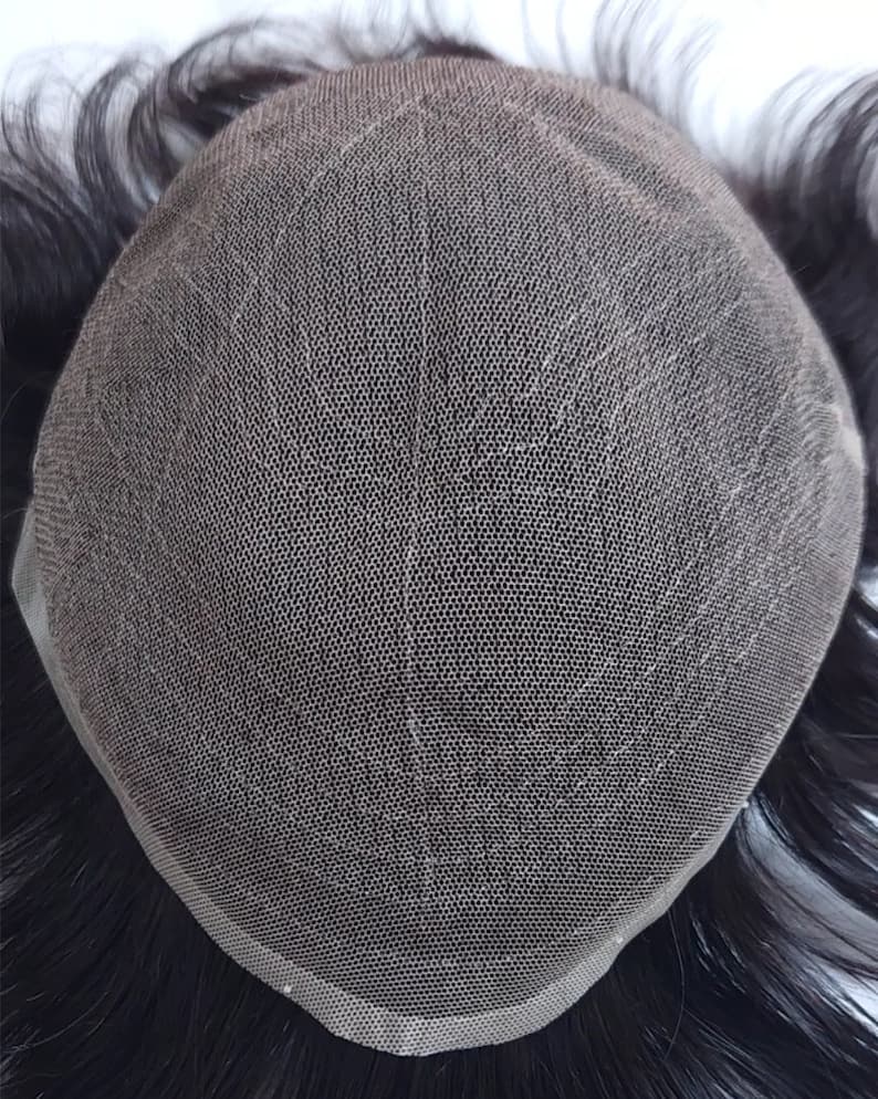 Puede incluir: Primer plano de una peluca con una base de malla negra y cabello humano negro. La peluca est&aacute; dise&ntilde;ada para ser fijada al cuero cabelludo para cubrir las zonas calvas o el cabello fino.