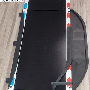 Könnte beinhalten: Eine schwarze Rennstrecke mit blauen und weißen Pfeilen auf der linken Seite und roten und weißen Pfeilen auf der rechten Seite. Die Strecke hat einen Kurvenabschnitt auf der rechten Seite. Der Text "Rechte Version" ist in der oberen rechten Ecke des Bildes sichtbar.