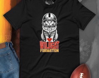 Könnte beinhalten: Schwarzes T-Shirt mit einem Grafikdruck eines Katers, der einen Footballhelm trägt und ein rotes Herz hält. Der Text "Wildcat Formation" ist unter dem Kater aufgedruckt.