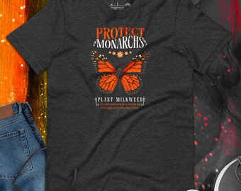 Könnte beinhalten: Dunkelgraues T-Shirt mit einem orangefarbenen Monarchfalter-Design und dem Text "PROTECT MONARCHS" und "PLANT MILKWEED". Das Design des Shirts enthält den Text "The only plant where monarchs lay their eggs and caterpillars thrive."