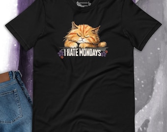 Puede incluir: Camiseta negra con un gato naranja de dibujos animados con los ojos cerrados y el texto "I HATE MONDAYS" impreso en ella.