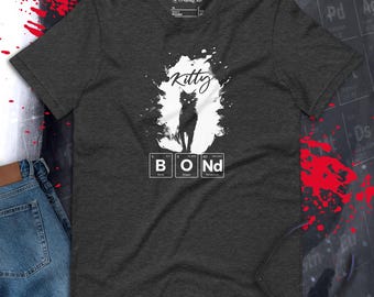 May include: A dark grey t-shirt with a white graphic of a black cat and the text "Kitty Bond" with the letters B, O, and Nd representing the chemical elements Boron, Oxygen, and Neodymium.