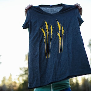 Könnte beinhalten: Ein dunkelgraues T-Shirt mit einer gelben Grafik von Weizenähren.