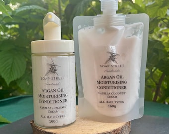 Può includere: Due contenitori di balsamo idratante all'olio di Argan fatto a mano di Soap Street. Uno è un barattolo di vetro trasparente con una pompa, l'altro un sacchetto flessibile. Entrambi sono etichettati "Vanilla Coconut Cream" e "All Hair Types", ciascuno contenente 160g.