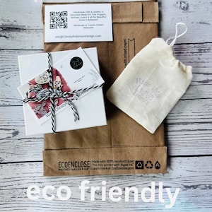 May include: Eco-friendly packaging featuring a white box tied with twine, a small drawstring bag, and a brown paper mailer. The mailer has the text "ECOENCLOSE" and "eco friendly packaging". A business card is visible with the text "Handmade Gifts & Jewelry".