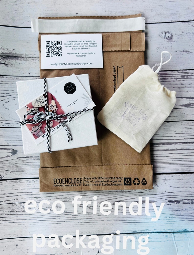 May include: Eco-friendly packaging featuring a white box tied with twine, a small drawstring bag, and a brown paper mailer. The mailer has the text "ECOENCLOSE" and "eco friendly packaging". A business card is visible with the text "Handmade Gifts & Jewelry".