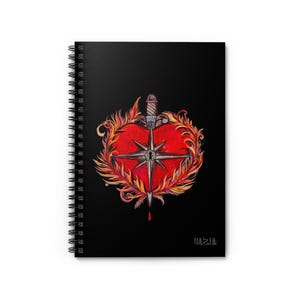 May include: A black spiral notebook with a red heart pierced by a dagger. The heart is surrounded by flames and a star with a keyhole in the center. The text "Oh, the irony" is printed in pink at the bottom.