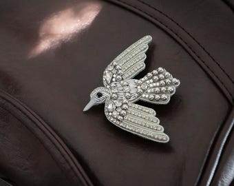 Un broche de cuentas con forma de pájaro plateado