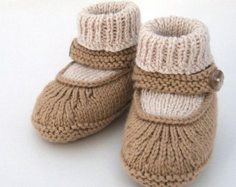 Peut inclure: Une paire de chaussons en tricot pour bébé en marron et beige avec un détail bouton. Les chaussons ont une bride sur le dessus et un revers rabattable.