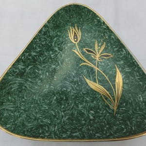 May include: Triangular green dish with a gold rim and a gold floral design. The dish has a swirled pattern in shades of green. The floral design features a stylized flower and leaves.