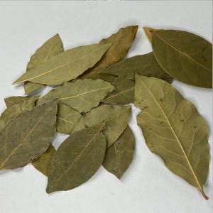 May include: A pile of dried bay leaves, a common spice used in cooking.