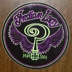 Puede incluir: Una pegatina redonda negra y morada con un logotipo estilizado que dice "Indian Larry" en una fuente de letra blanca. El logotipo presenta una "P" verde estilizada con alas y una cruz con los años "1949" y "2004" debajo.