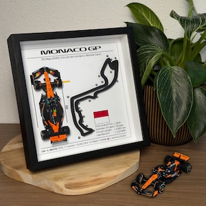 Peut inclure: Impression encadrée du circuit du Grand Prix de Monaco avec une voiture de course miniature. L'impression comprend le texte "MONACO GP" et les détails de la course. La voiture de course est noire et orange. Le cadre est noir.