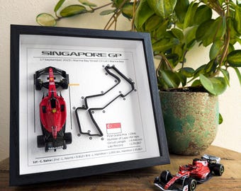 May include: A framed black and white print of the Singapore Grand Prix race track with a red miniature race car. The print includes the date of the race, September 17, 2025, and the name of the track, Marina Bay Street Circuit. The print also includes the first Grand Prix date, number of laps, circuit length, and lap record.
