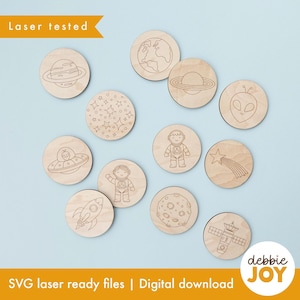 May include: A set of twelve circular light wood discs featuring laser-engraved space-themed illustrations including planets, stars, an astronaut, a rocket, a satellite, a shooting star, a moon, a flying saucer, and an alien face.