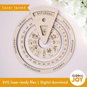 Op de afbeelding: Een houten eeuwige kalender met een cirkelvormig ontwerp. De kalender heeft roterende ringen voor dagen, data en maanden, met gegraveerde illustraties voor elke maand. De tekst "Laser tested" en "SVG laser ready files | Digital download" zijn zichtbaar.