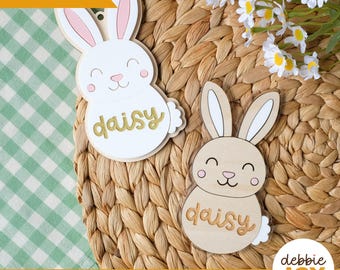 Puede incluir: Dos adornos de madera con forma de conejito con el nombre "daisy". Uno es blanco con detalles rosas, el otro es de madera natural. El texto "Laser tested" está en la esquina superior izquierda. El texto "SVG laser ready files | Digital download" está en la parte inferior.