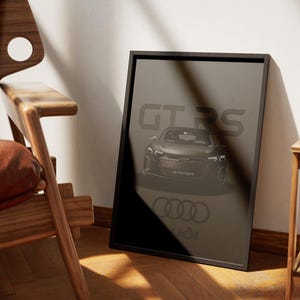 Puede incluir: Un póster en blanco y negro con un coche Audi R8 GT RS negro en el centro. El coche está de frente al espectador y el texto "GT RS" está por encima del coche. El logotipo de Audi está debajo del coche.