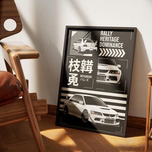 May include: Black framed poster featuring white Mitsubishi rally cars. The poster includes the text "Rally Heritage Dominance" and Japanese characters. The poster is displayed in a room with a wooden chair.
