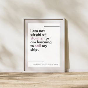 May include: White framed print with a quote by Louisa May Alcott from Little Women: "I am not afraid of storms, for I am learning to sail my ship."