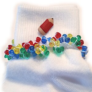 May include: White socks with a colorful beaded trim and a red pencil charm.