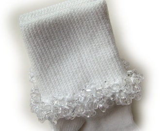 May include: White socks with a beaded trim around the top. The beads are clear and create a ruffled effect.