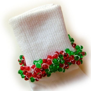 May include: White knitted sock with a beaded cuff. The cuff features red and green beads strung on white thread, creating a festive, holiday-themed design. The beads are small and round, adding a touch of sparkle to the sock.