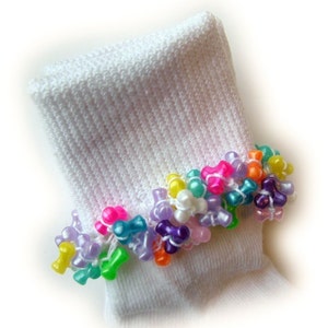 May include: White ankle socks with a colorful beaded trim. The beads are in the shape of bows and are in various colors, including pink, purple, green, blue, and yellow.