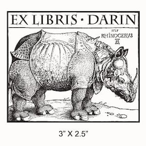 Könnte beinhalten: Schwarzweiß-Illustration eines Nashorns mit dem Text "EX LIBRIS. DARIN" und "1515 RHINOCERVS" über dem Bild. Das Bild ist 7,6 cm x 6,4 cm groß.