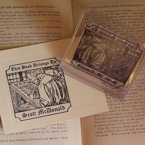 May include: A black and white illustration of a person sitting at a table with a book. The text "This Book Belongs To Scott McDonald" is printed below the illustration.