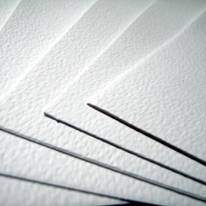 Puede incluir: Una pila de hojas de papel blanco con una textura prensada en fr&iacute;o distintiva. Las hojas est&aacute;n dispuestas en un patr&oacute;n superpuesto en abanico, resaltando la superficie rugosa y granular del papel y los bordes limpios y afilados de cada hoja.