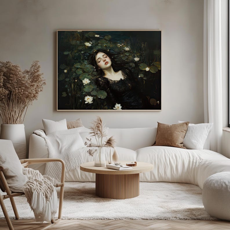 May include: A framed art print shows a woman in a black dress amongst lily pads and white flowers. The artwork has a dark colour palette and is displayed above a white sofa in a living room setting.