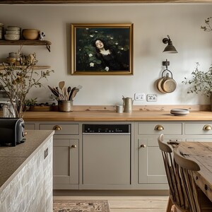 May include: A kitchen featuring light grey cabinets, wooden worktops, and a framed painting. The painting shows a woman surrounded by white flowers. Kitchen utensils and copper pans hang on the wall. A black dishwasher is integrated into the cabinetry.